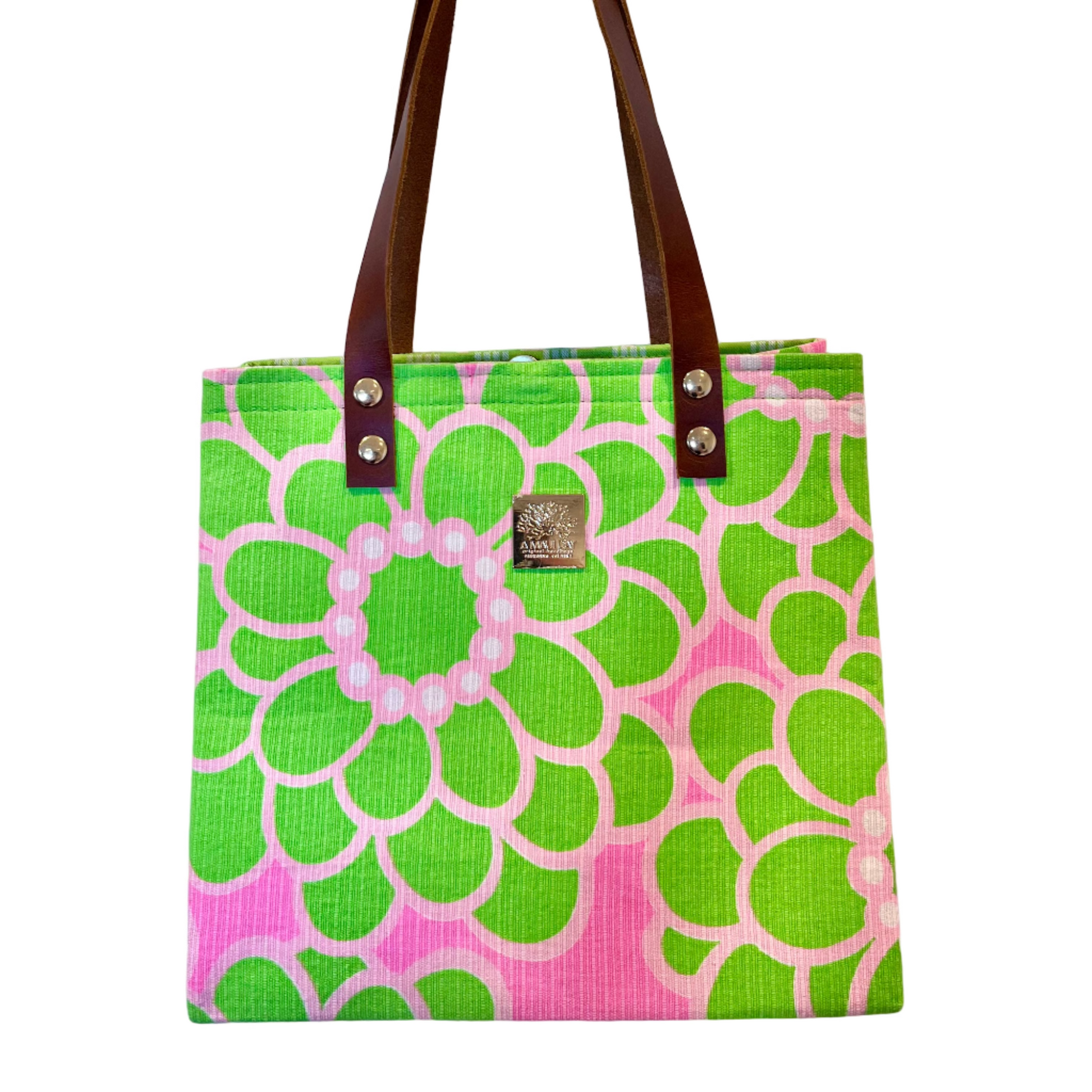 Green and pink patterned tote bag with brown handles on a white background